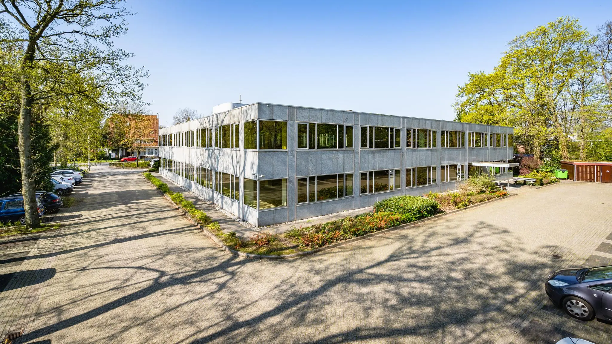 Kantoorpand aan de Utrechtseweg met parkeergelegenheid en omliggend groen op een zonnige dag.