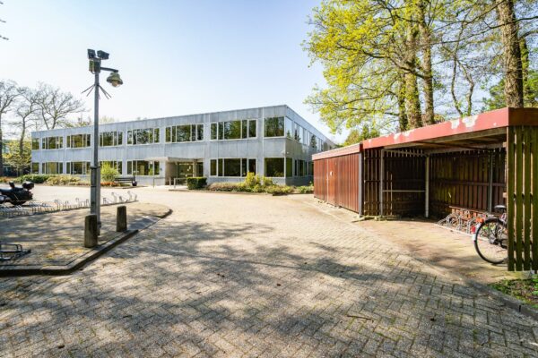 Voorzijde van een modern kantoorgebouw aan de Utrechtseweg met fietsenstalling en parkeerplaats.