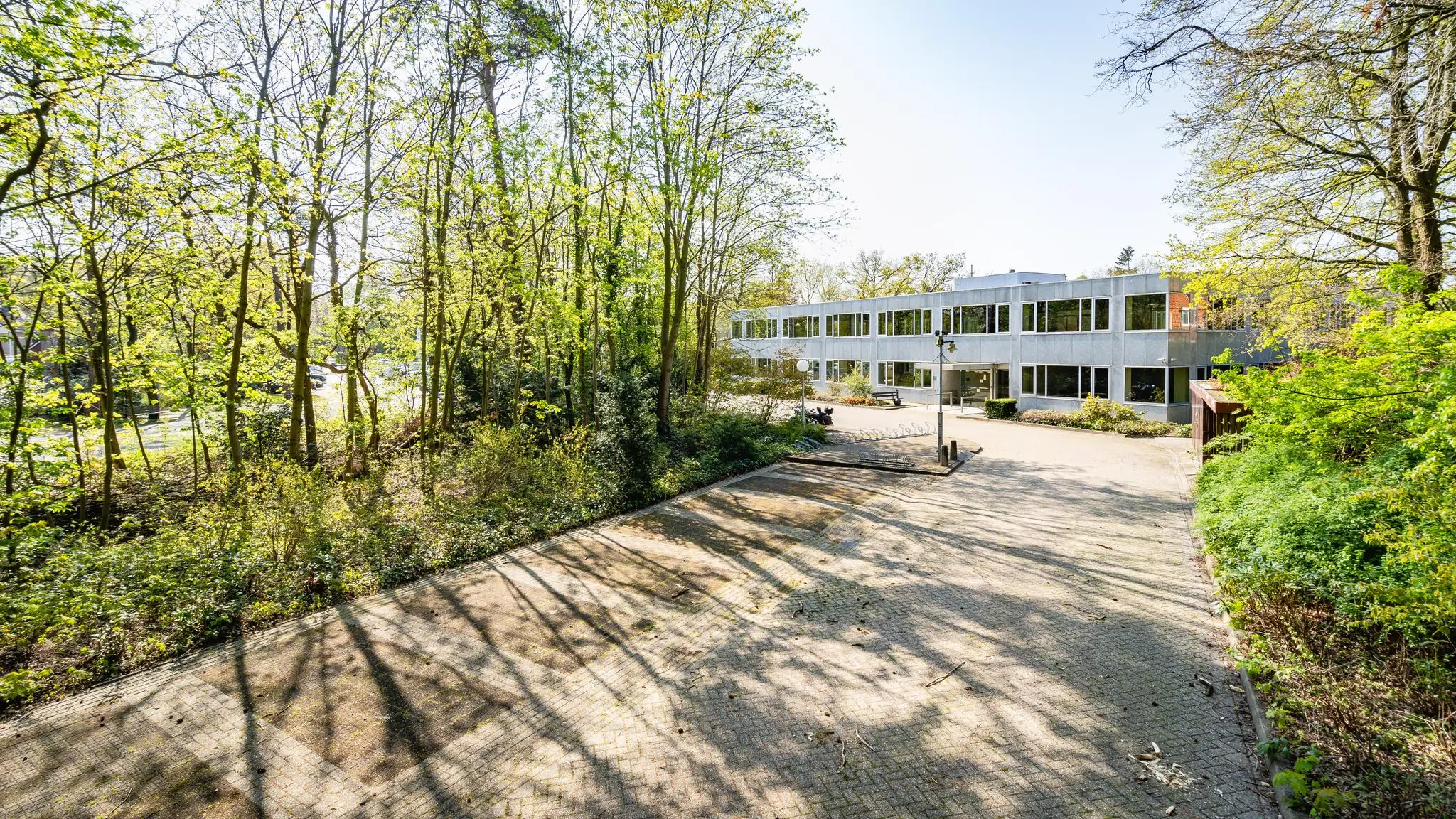 Modern kantoorgebouw aan de Utrechtseweg, omringd door een groene, bosrijke omgeving.