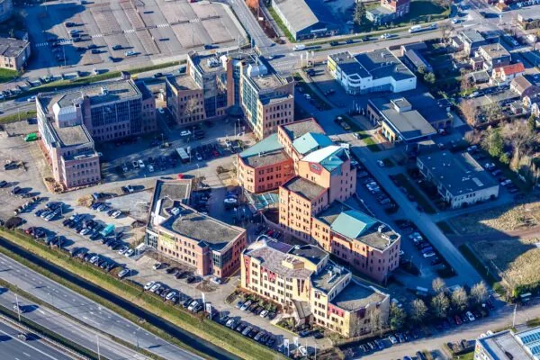 Luchtfoto van het kantoorgebouwcomplex Kosterijland in een stedelijke omgeving met omliggende wegen en parkeerterreinen.