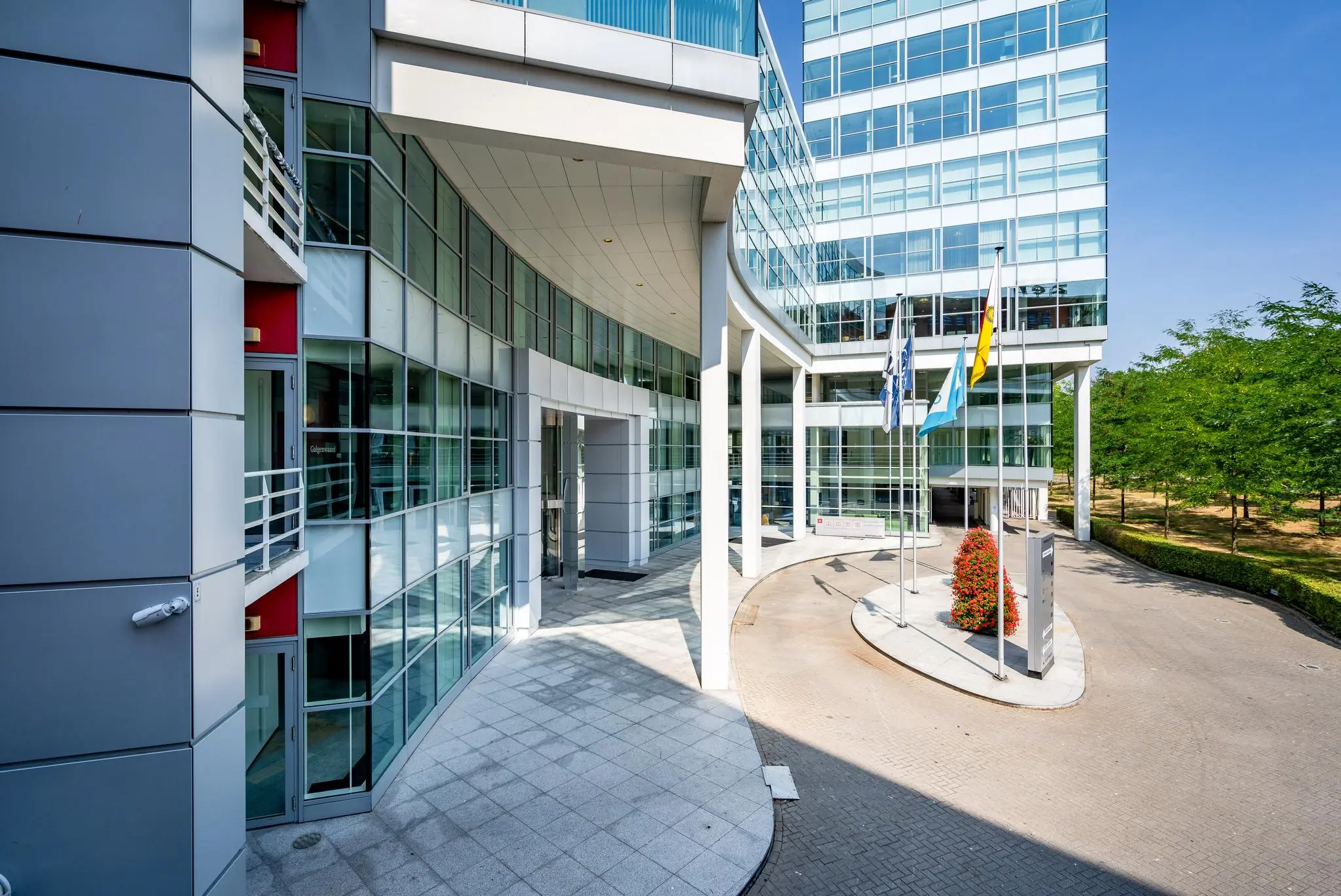 Moderne kantoorgebouwen aan de Newtonlaan met glazen gevels, vlaggen en een oprijlaan.