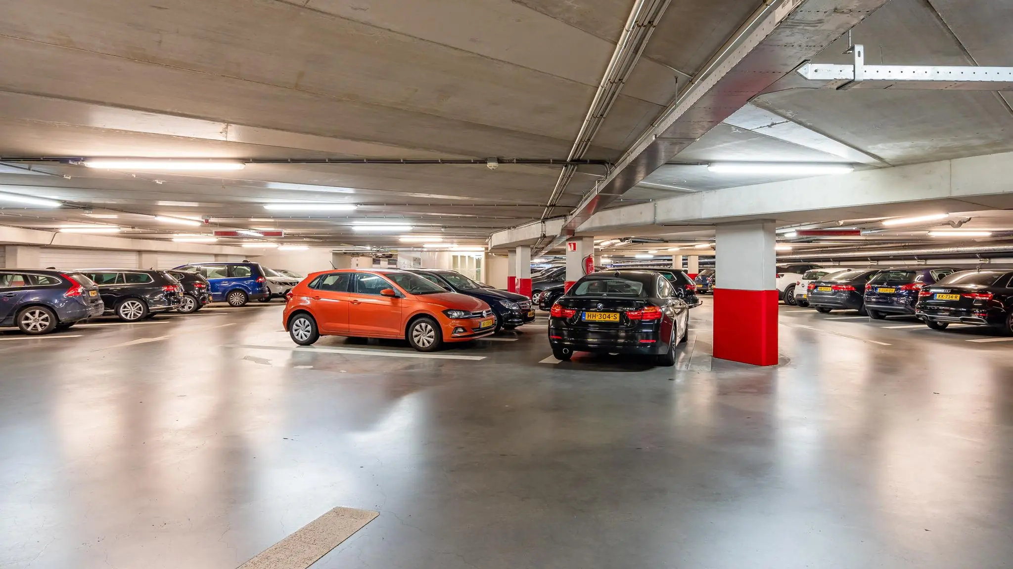 Ondergrondse parkeergarage aan de Newtonlaan met geparkeerde auto's in goed verlichte omgeving.
