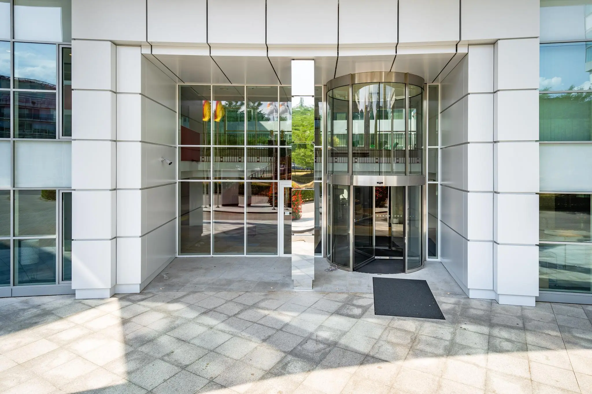 Ingang van een modern kantoorgebouw aan de Newtonlaan met een glazen draaideur en strakke gevelbekleding.