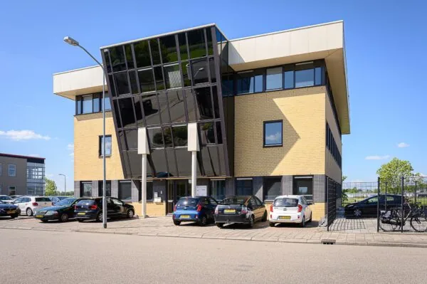 Modern kantoorgebouw aan de Spoorhaven met gele bakstenen en grote, schuine glazen gevel.