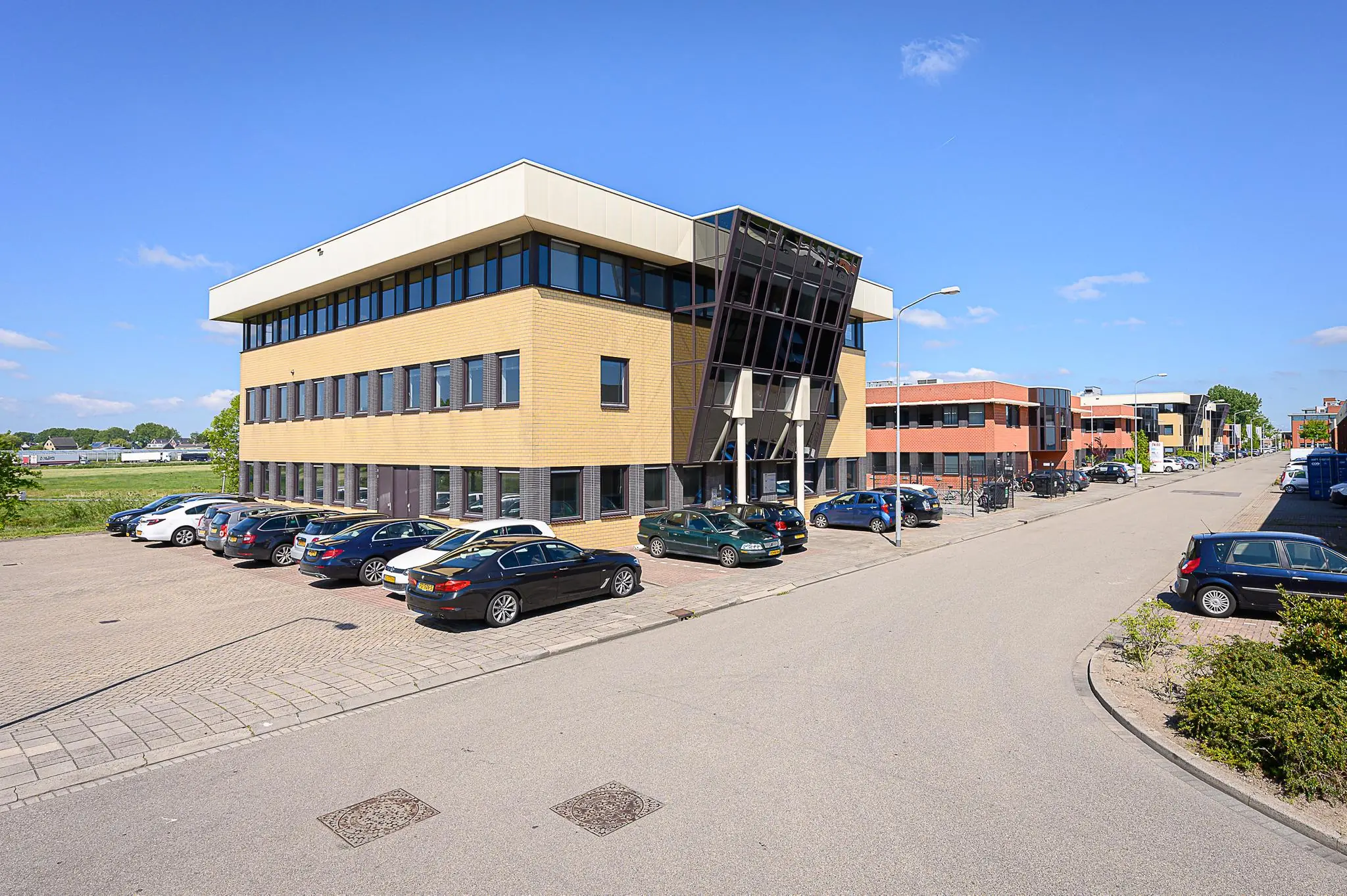Zakelijk kantoorgebouw aan de Spoorhaven met geparkeerde auto's op een zonnige dag.