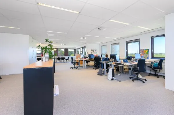 Modern kantoorinterieur in Spoorhaven met werkplekken, computers en mensen aan het werk.