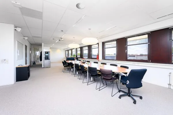 Vergaderruimte in een modern kantoor aan de Spoorhaven met lange tafel, stoelen en grote ramen.