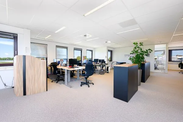 Moderne, open kantoorruimte aan de Spoorhaven met meerdere bureaus, bureaustoelen, computers en veel daglicht.