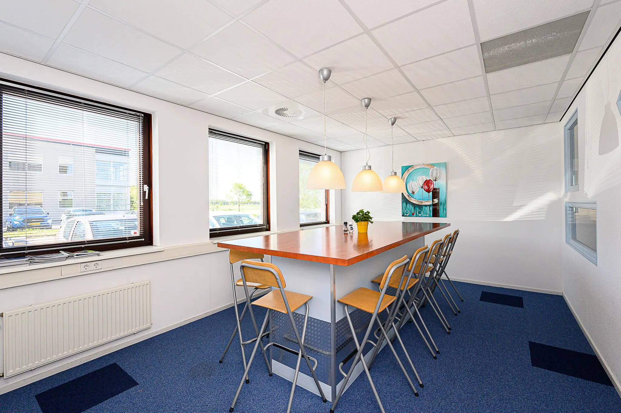 Vergaderruimte met hoge tafel, barkrukken, drie hanglampen en grote ramen in een kantoorpand aan de Spoorhaven.