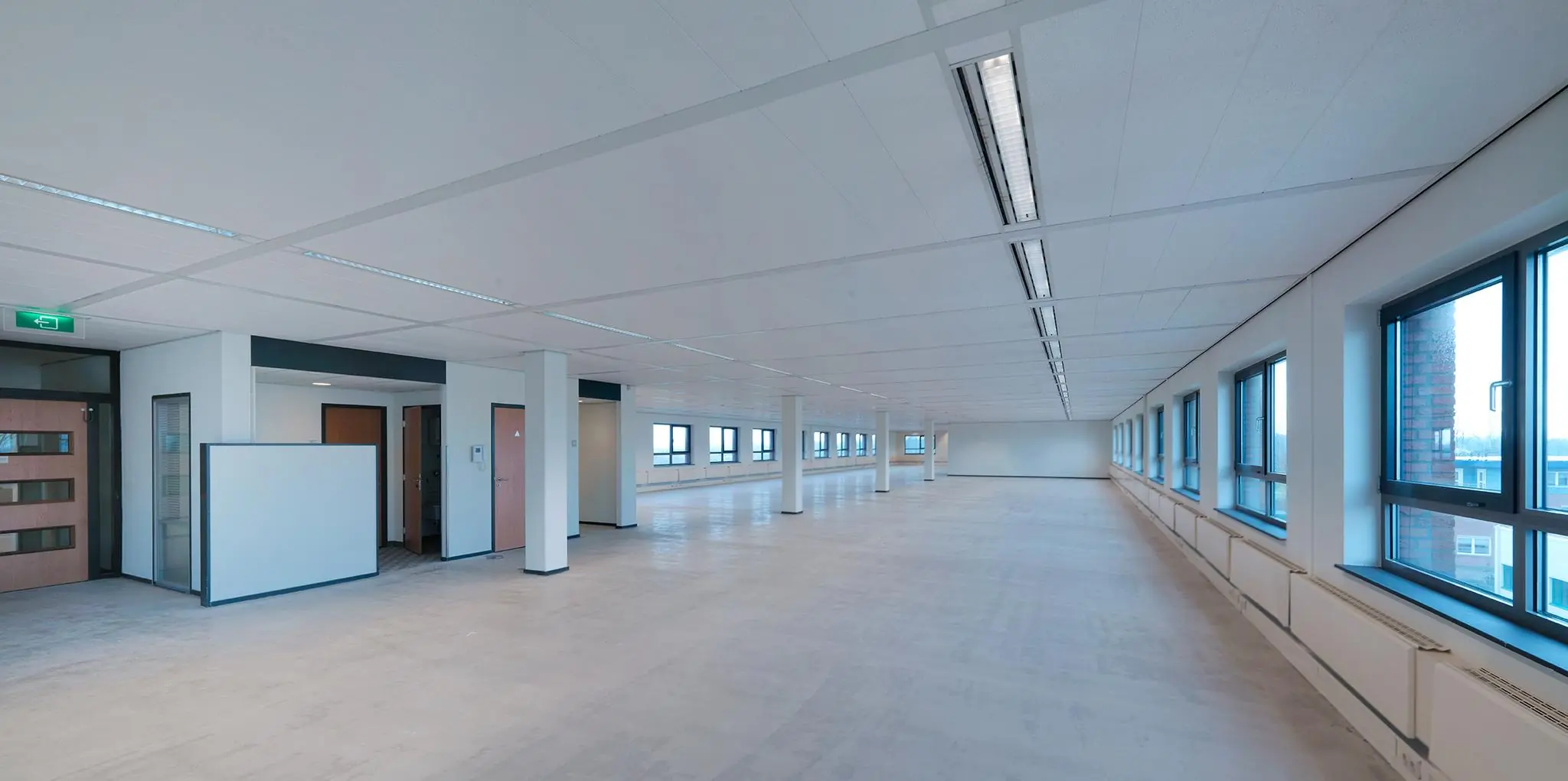 Leeg en modern kantoorruimte-interieur aan de Pompmolenlaan met grote ramen en systeemplafond.