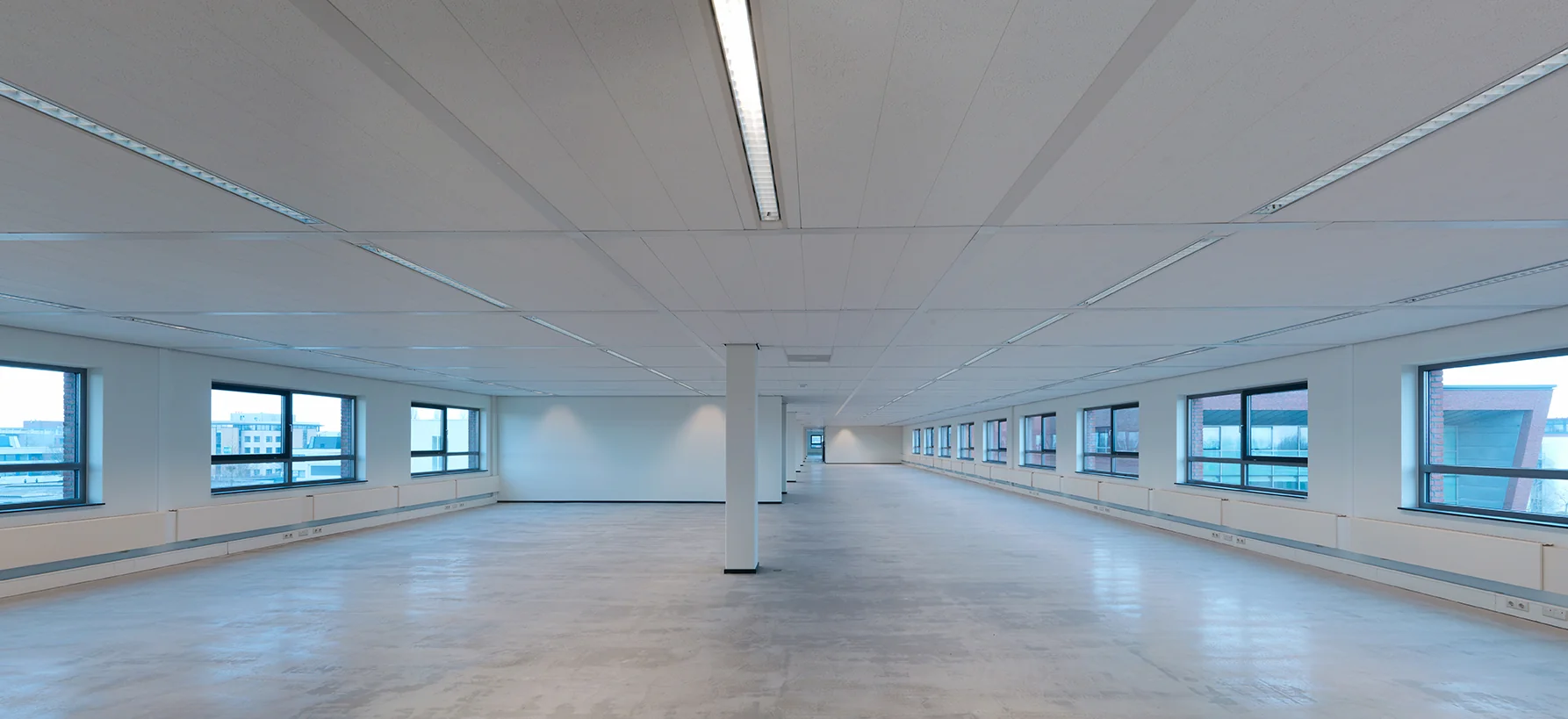 Leeg en modern kantoorpand aan de Pompmolenlaan met grote ramen en systeemplafond.