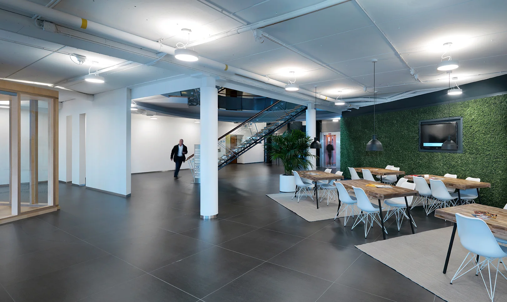 Moderne kantoorruimte aan de Pompmolenlaan met zithoeken, moswand en glazen trapopgang.
