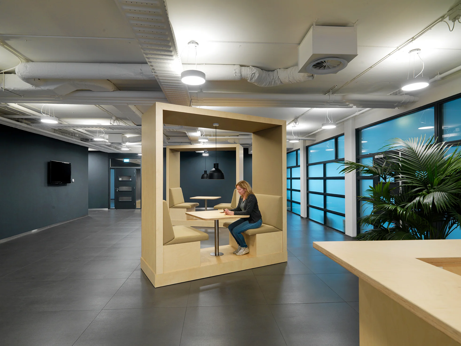 Vrouw werkt op een laptop in een moderne kantoorruimte aan de Pompmolenlaan met ingebouwde zithoek.