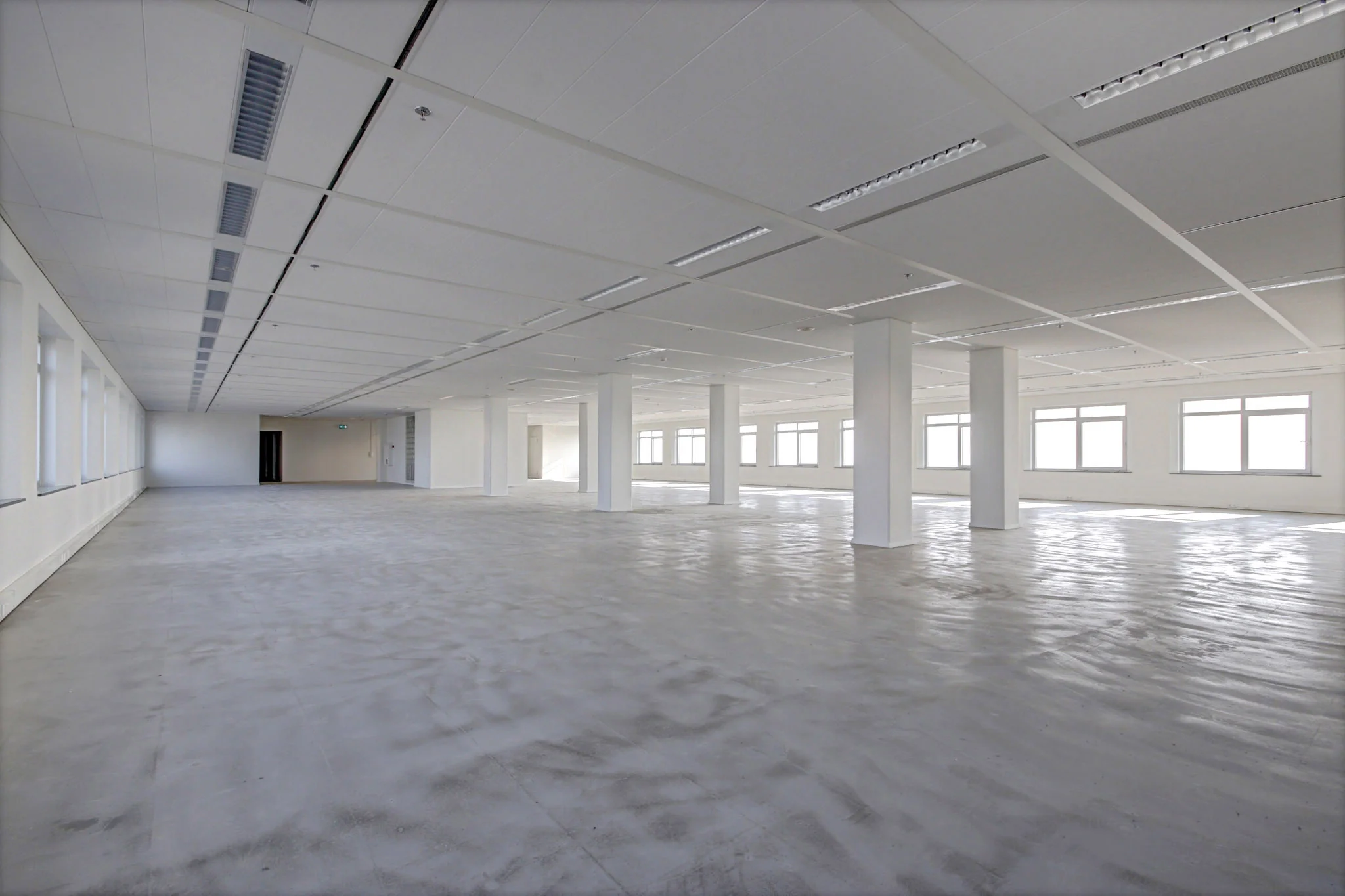 Leeg en ruim kantoorgebouw aan de Winthontlaan met betonnen vloer en grote ramen.