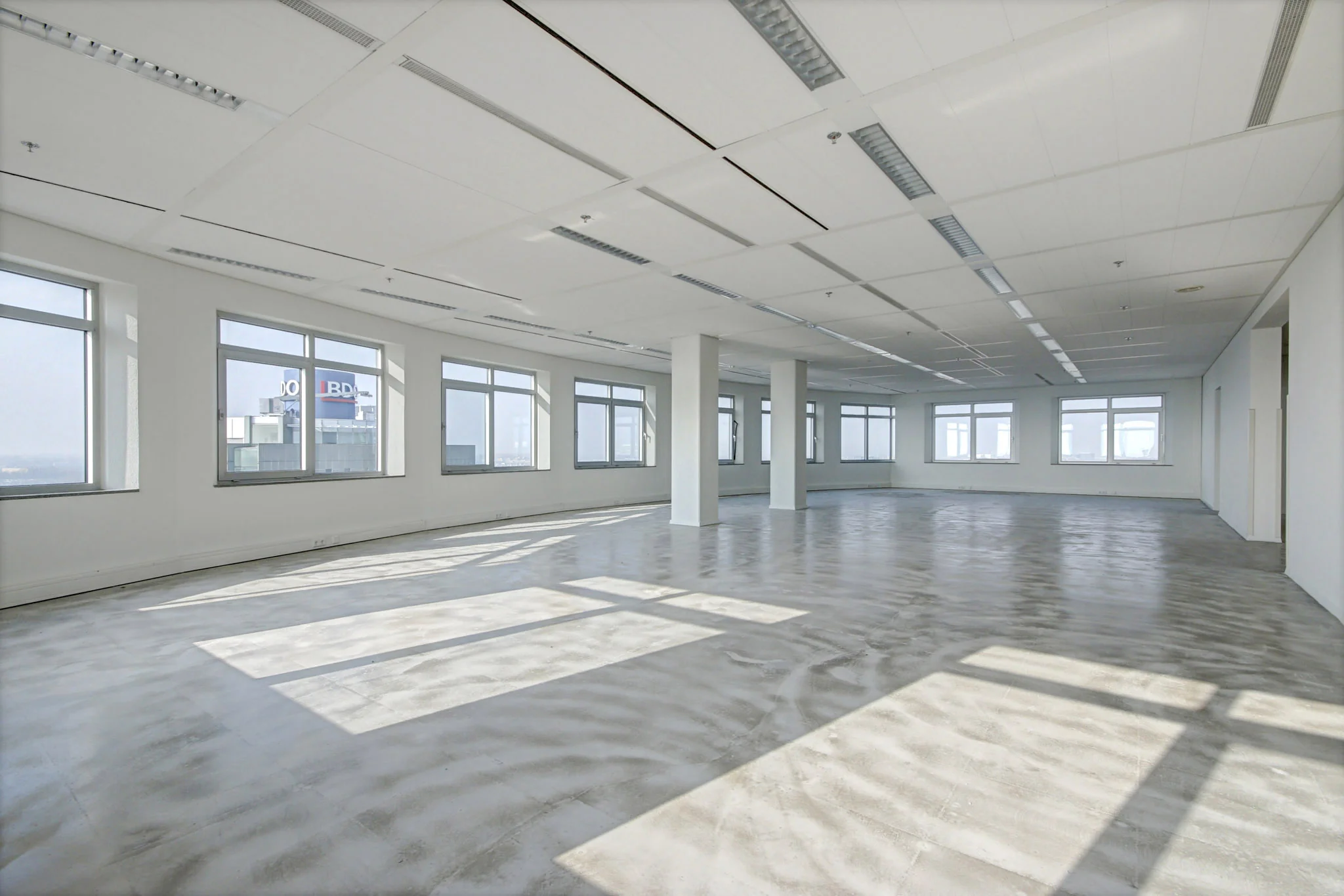 Lichte, lege kantoorruimte aan de Winthontlaan met grote ramen en betonnen vloer.