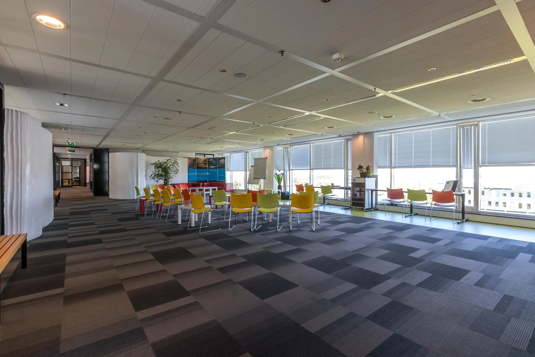 Moderne kantoorruimte op Newtonlaan met kleurrijke stoelen, een open zitgedeelte en veel daglicht.