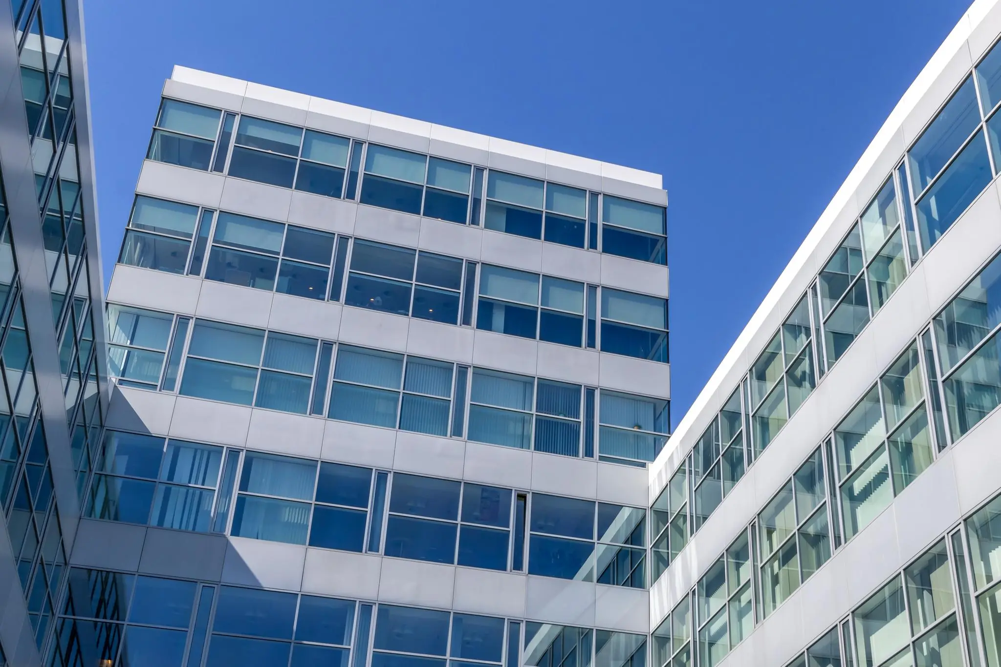 Modern kantoorgebouw aan de Newtonlaan met glazen gevels en een heldere blauwe lucht op de achtergrond.