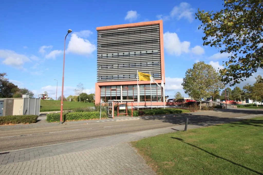 Kantoorgebouw aan de Marconibaan met vlaggen en een heldere blauwe lucht op de achtergrond.