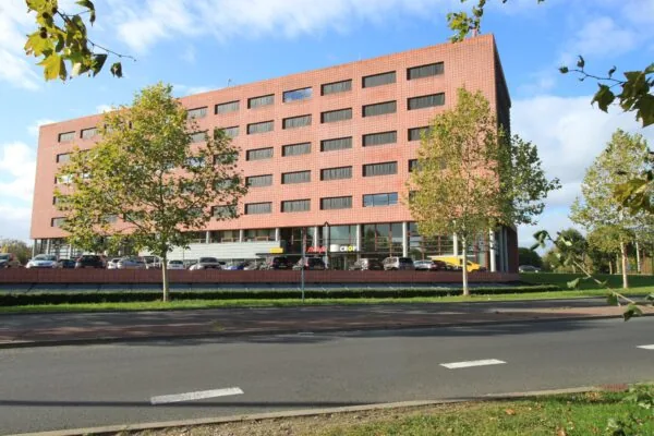 Kantoorgebouw aan de Marconibaan met een rode gevel en parkeerplaatsen aan de voorzijde.