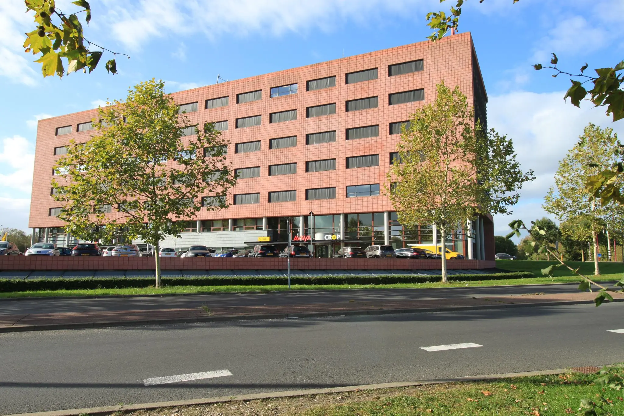 Kantoorgebouw aan de Marconibaan met een rode gevel en parkeerplaatsen aan de voorzijde.