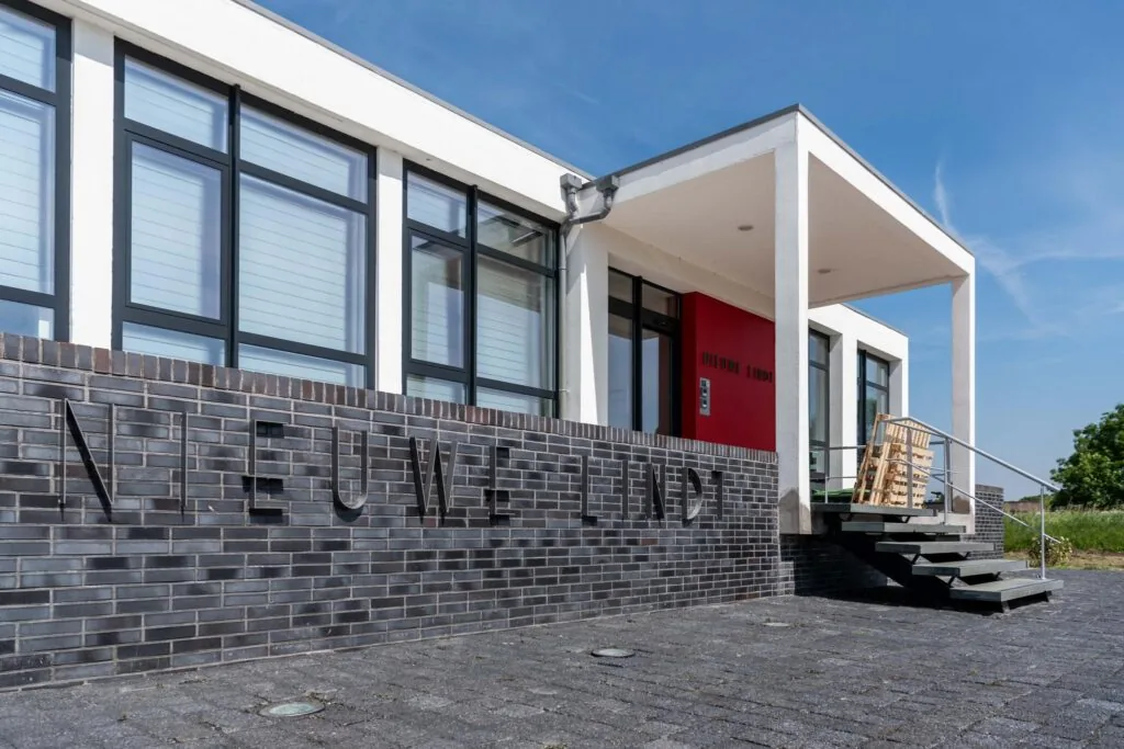 Moderne voorgevel van gebouw 'Nieuwe Lindt' met grote ramen en een rode entree.