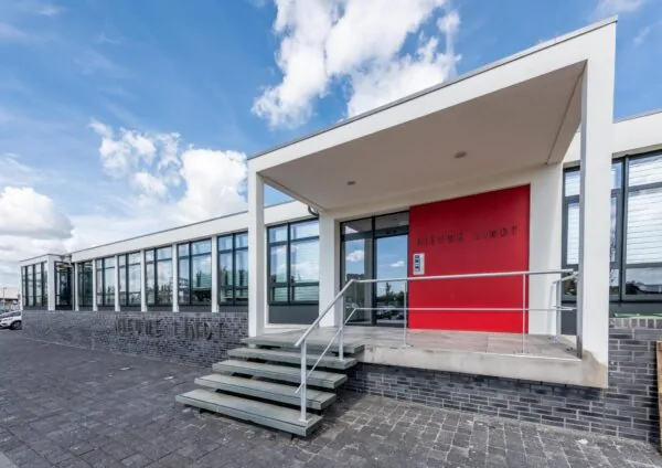 Vooraanzicht van het moderne bedrijfsgebouw Nieuwe Lindt aan de Lindtsedijk met brede ramen en een rood accent bij de entree.