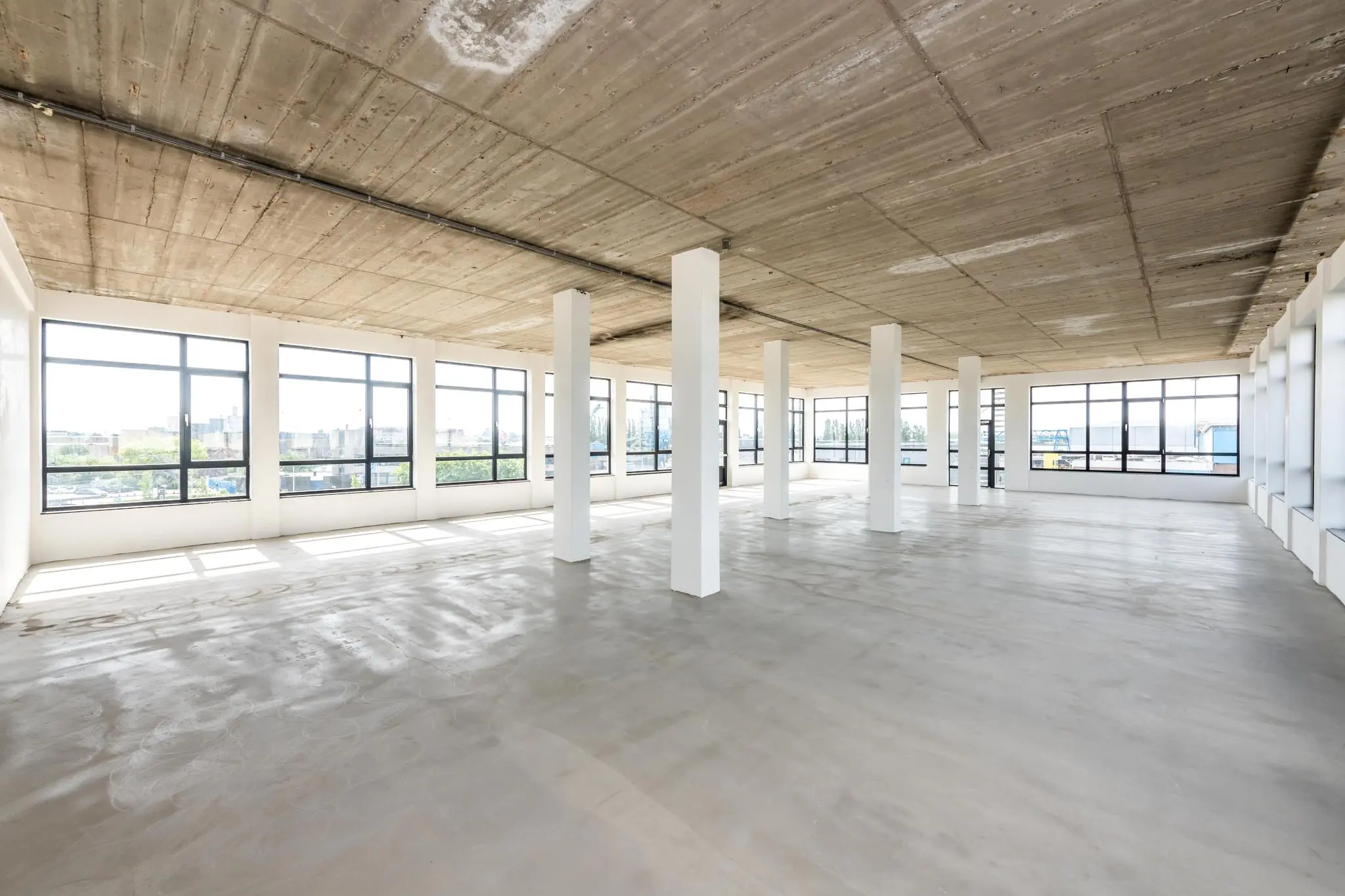 Lichte, lege kantoorruimte aan de Lindtsedijk met betonnen plafond en grote ramen rondom.
