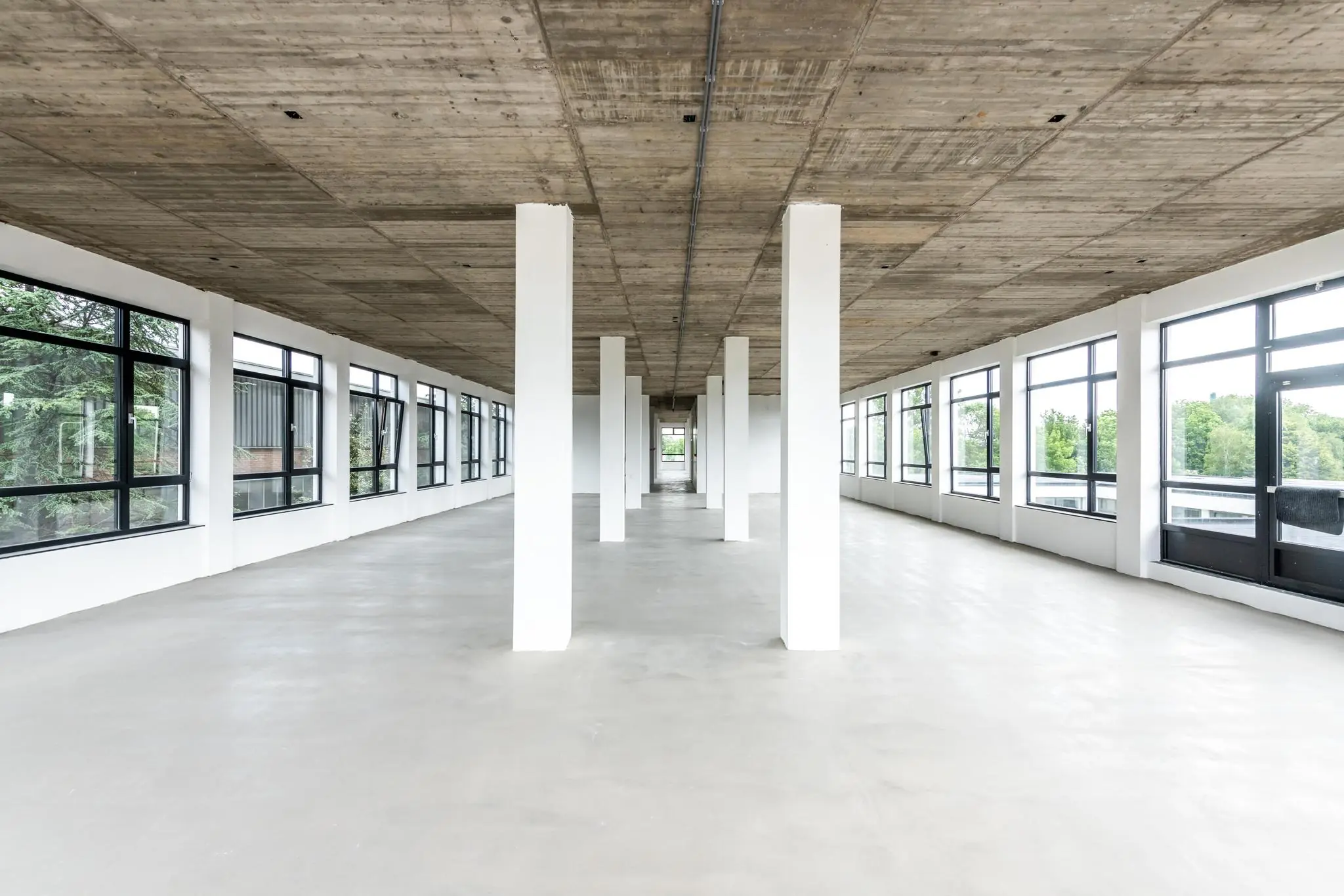 Licht en ruimtelijk industrieel kantoorpand aan de Lindtsedijk met betonnen plafond en grote ramen.