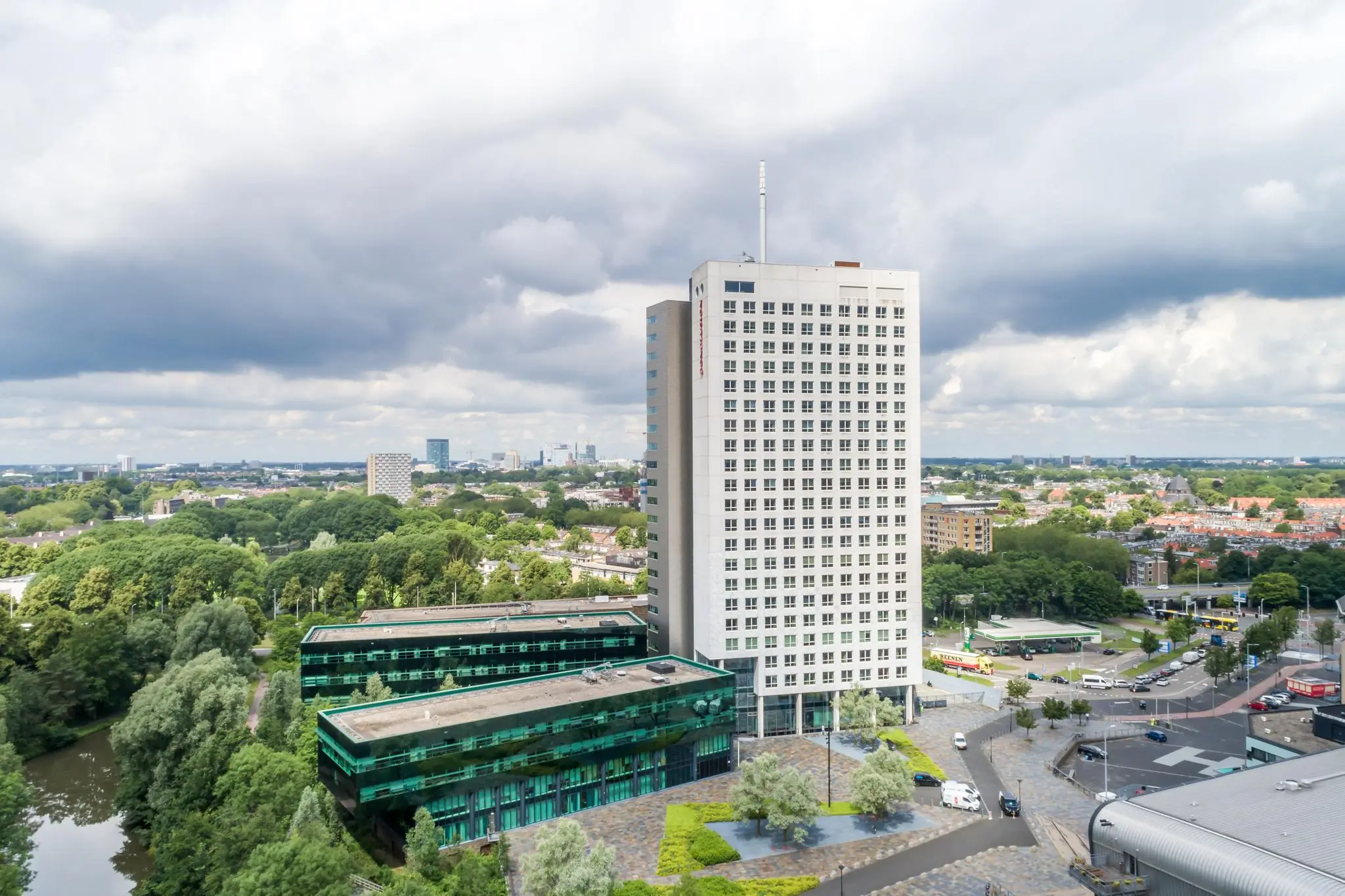 Hoog gebouw aan het Herculesplein in Utrecht met omliggend groen en stadszicht onder een bewolkte hemel.