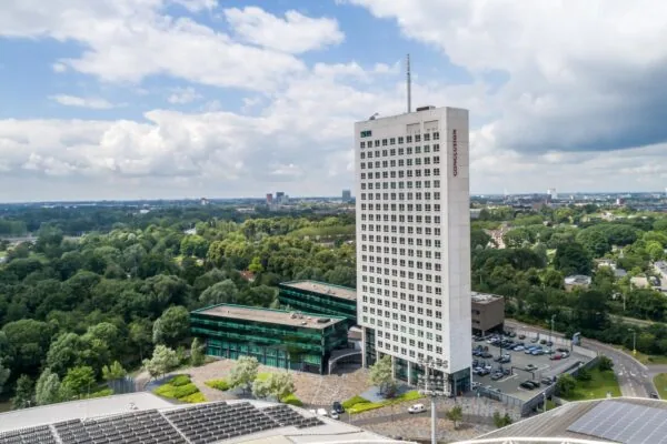 Hoog kantoorgebouw aan het Herculesplein in Utrecht, omringd door groen en parkeerplaatsen.