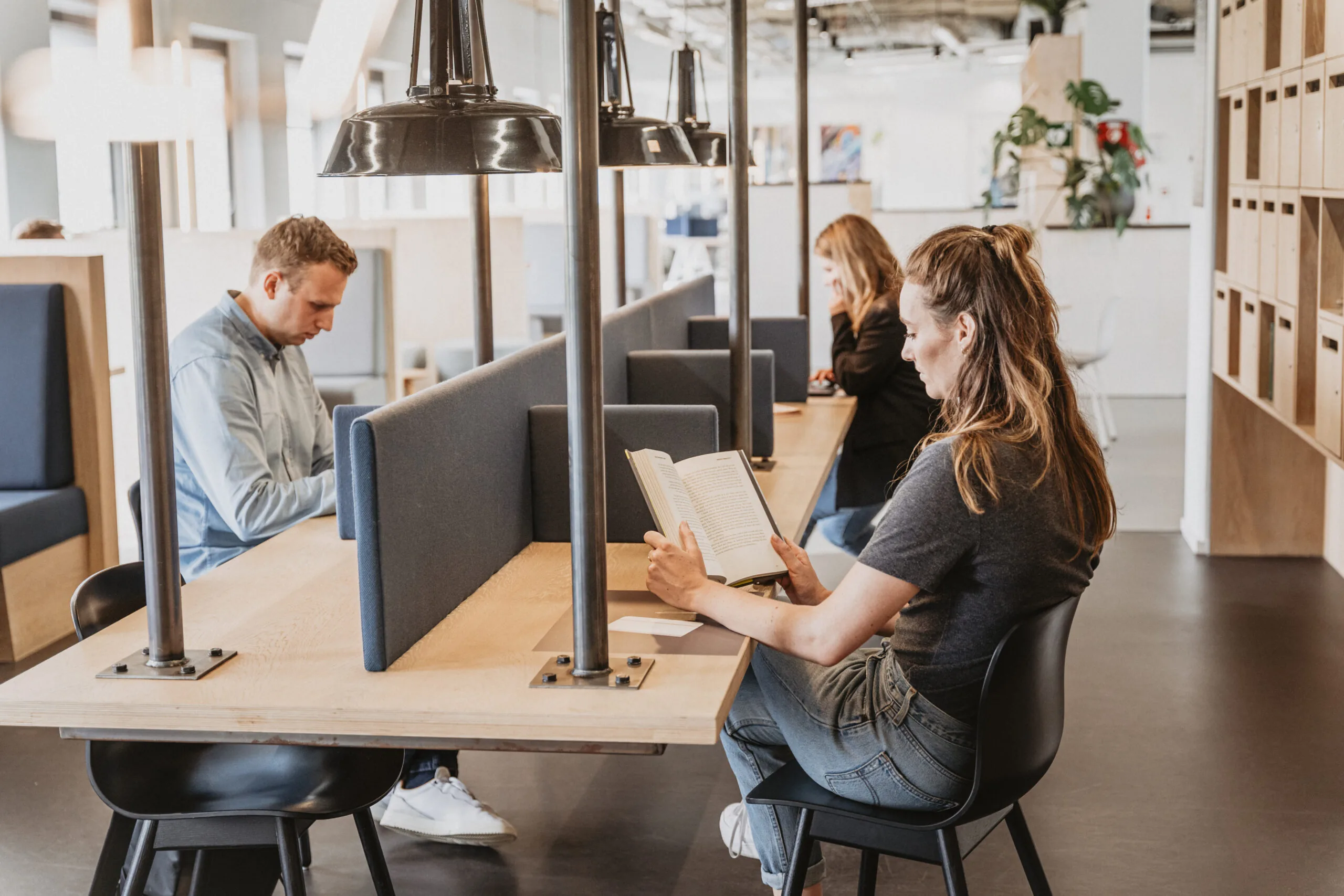 Mensen werken en lezen geconcentreerd in een moderne, gedeelde werkruimte bij HNK Utrecht CS.