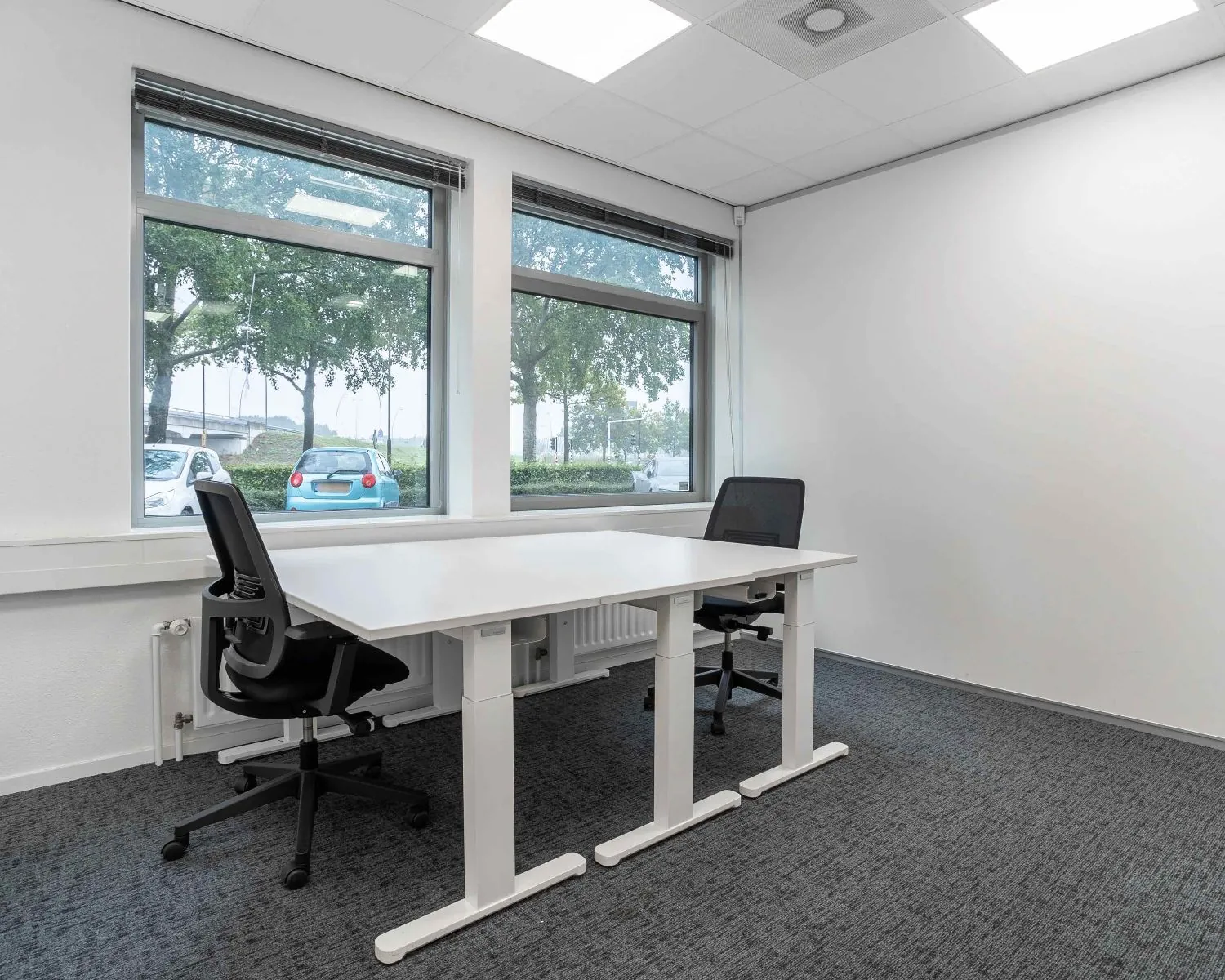 Modern ingericht kantoor met twee bureaus en grote ramen aan de Hurksestraat 43 in Eindhoven.