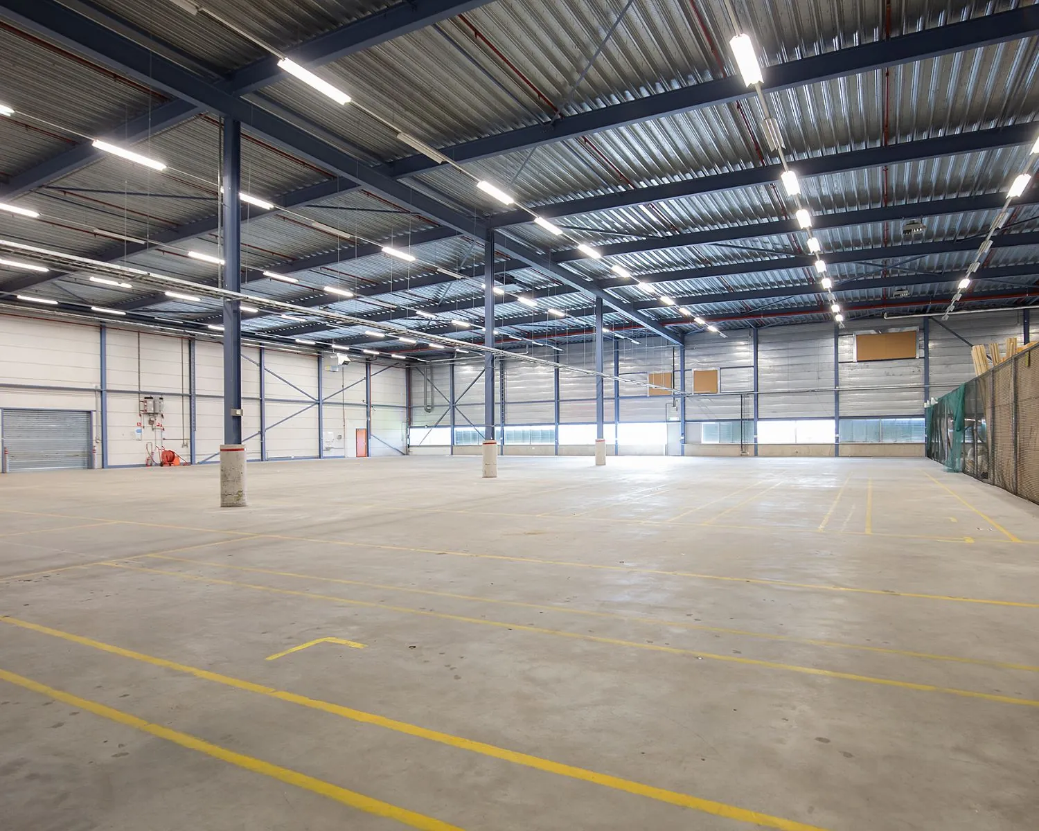 Ruime, lege bedrijfshal met hoge plafonds aan de Albert Einsteinweg 5 in Lelystad.