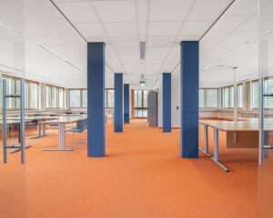 Moderne, open kantoorruimte met oranje vloerbedekking en werkplekken aan de Bolderweg 1 in Almere.