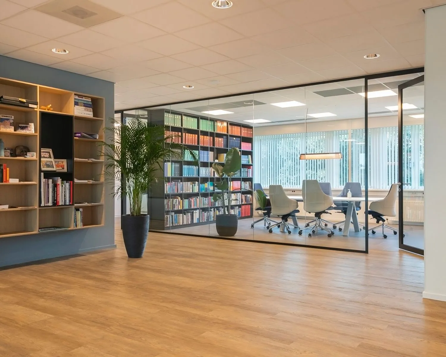 Moderne kantoorruimte aan de Bolderweg 2a in Almere met glazen vergaderruimte, houten vloer en open boekenkasten.