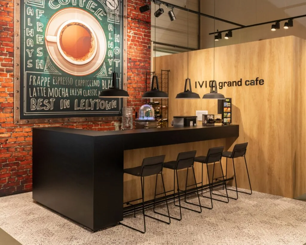 Moderne grand café-hoek met zwarte bar, hoge stoelen en een grote koffiekunstwand in kantoorruimte aan de Pascallaan 60-78 in Lelystad.