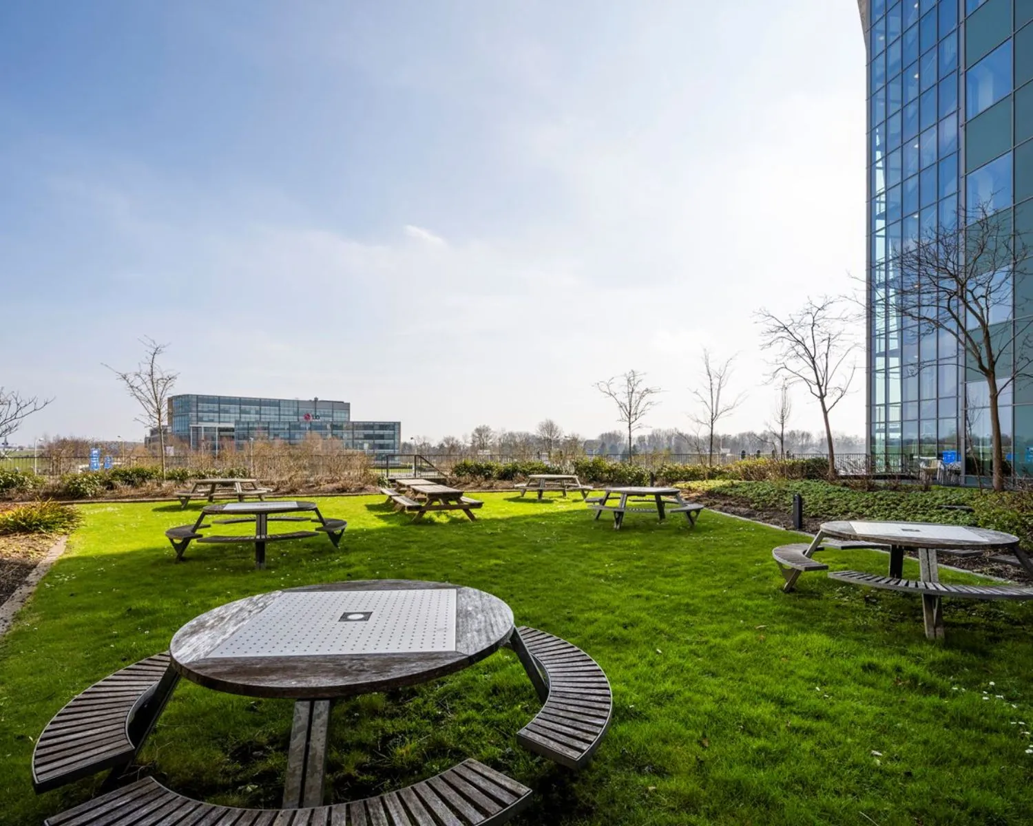 Groene buitenruimte met picknicktafels bij kantoorgebouw aan de Laan van Langerhuizen 1 in Amstelveen.