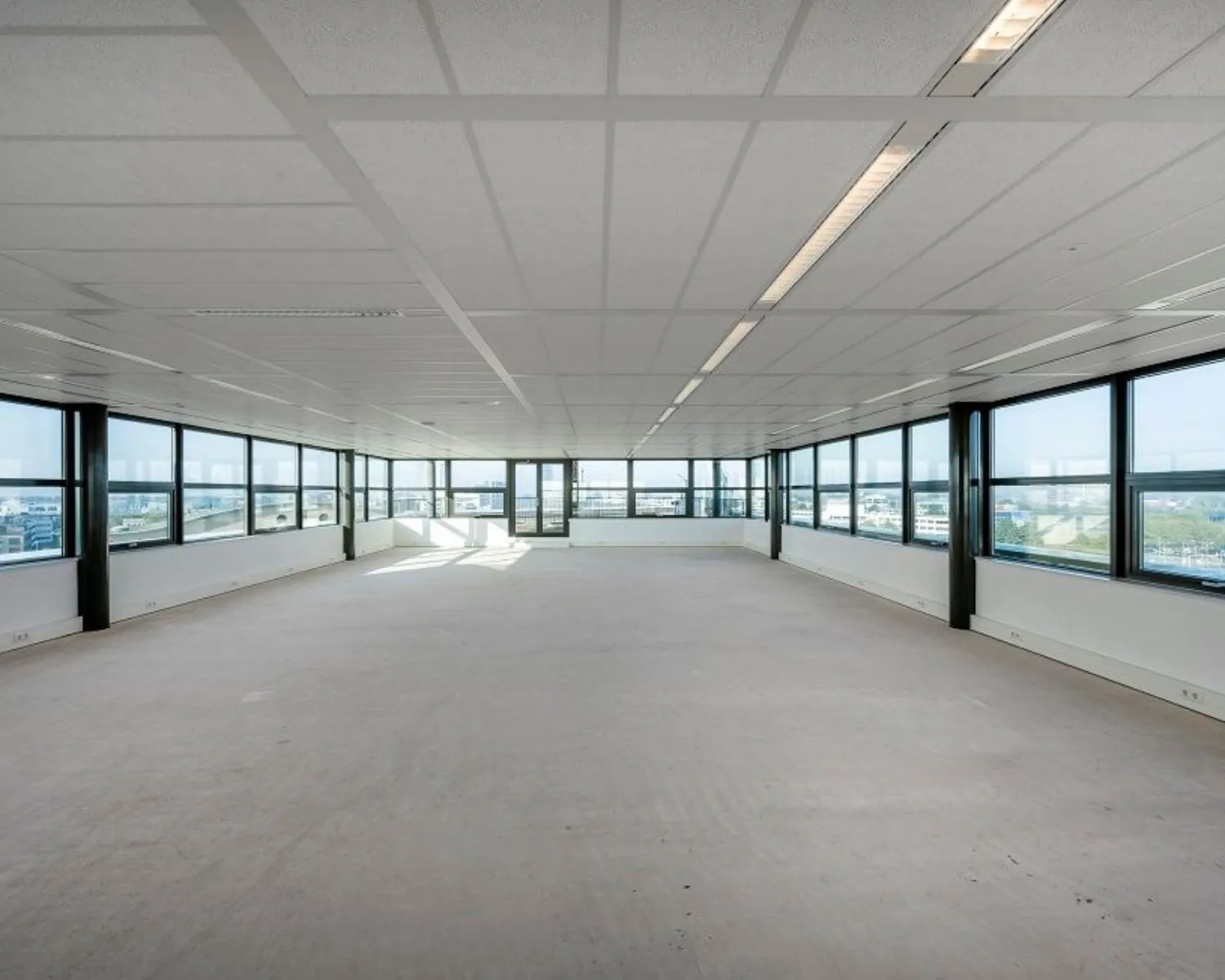 Leegstaande, lichte kantoorruimte te huur aan de Bloemlaan 2 in Hoofddorp met ramen rondom en uitzicht op de stad.