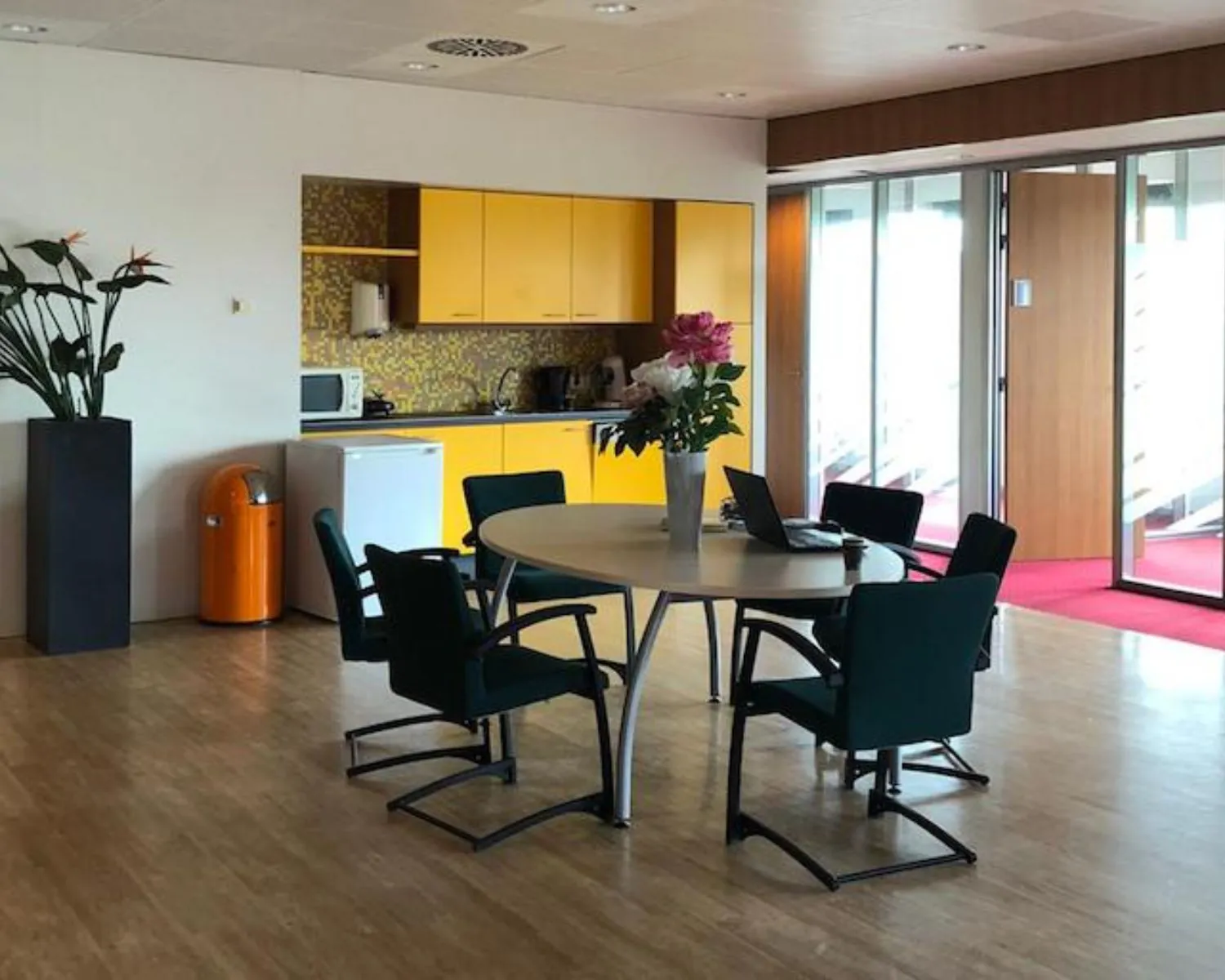 Moderne kantoorruimte aan de Kronenburgsingel 525 in Arnhem met vergadertafel, felgele keuken en grote raampartijen.