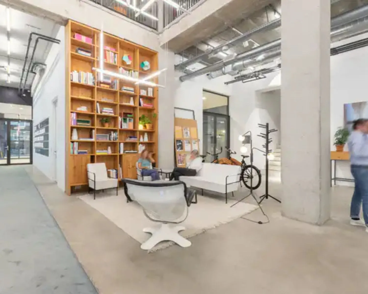 Moderne kantoorruimte aan de Vijzelstraat 60 in Amsterdam met hoge plafonds, een grote boekenkast en een informele zithoek.