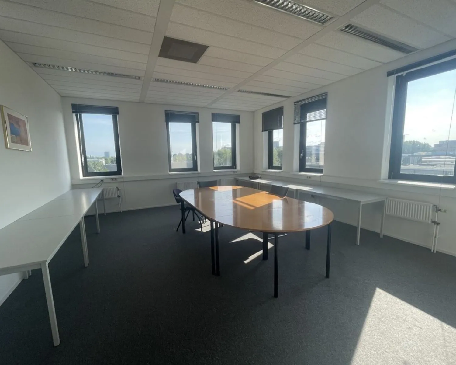 Lichte kantoorruimte met vergadertafel en meerdere bureaus aan de Zekeringstraat 17 in Amsterdam.