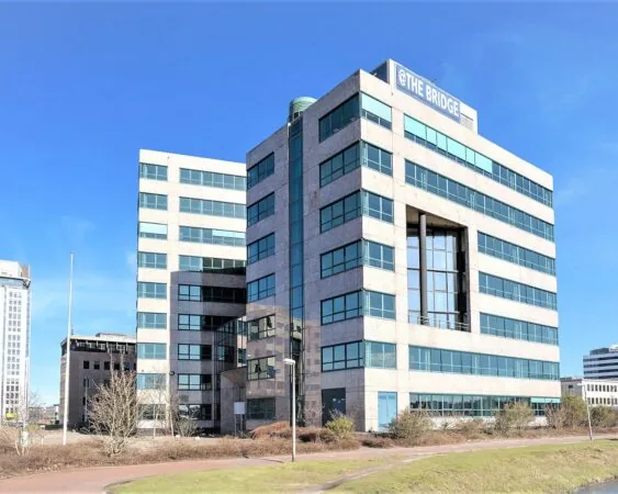Zijaanzicht van modern kantoorgebouw @The Bridge met glazen gevel en meerdere verdiepingen.