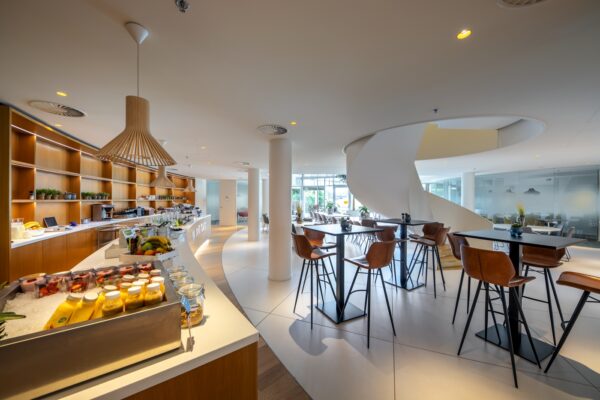 Moderne bedrijfsrestaurant aan de Euclideslaan met een buffet, hoge zitplaatsen en een spiraalvormige trap.