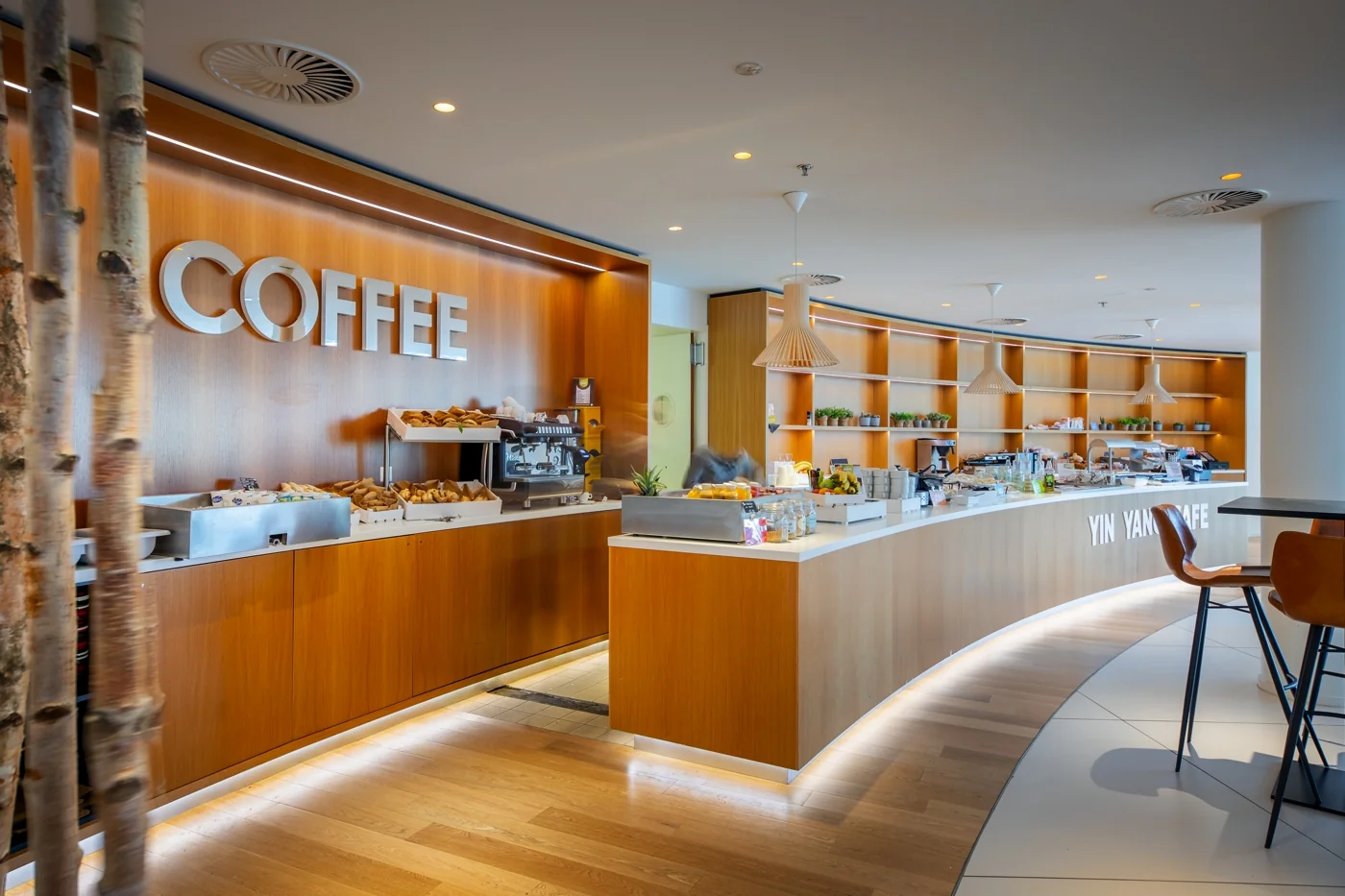 Modern café-interieur aan de Euclideslaan met houten afwerking, een koffiebar en het bord 'Yin Yang Café'.