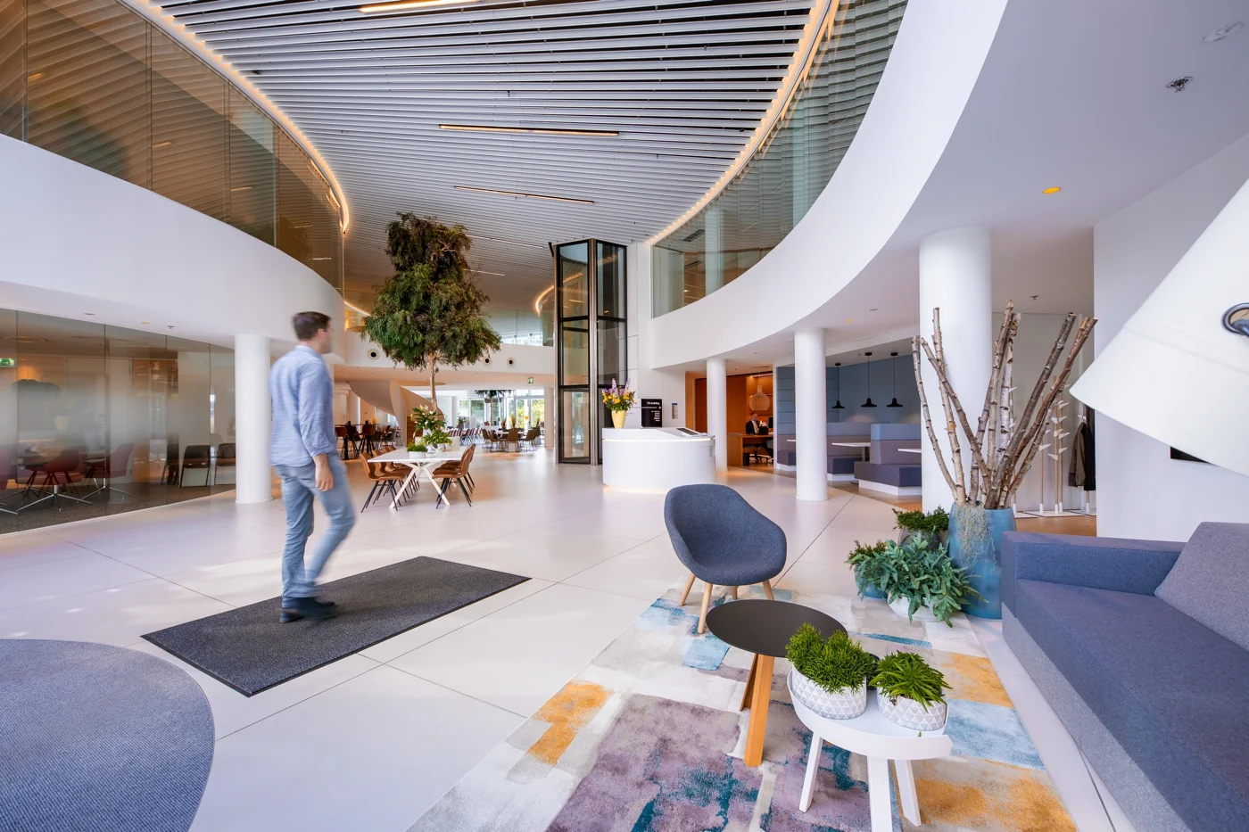 Moderne en ruime ontvangsthal van een kantoorpand aan de Euclideslaan met zithoeken, planten en een centraal gelegen receptiebalie.