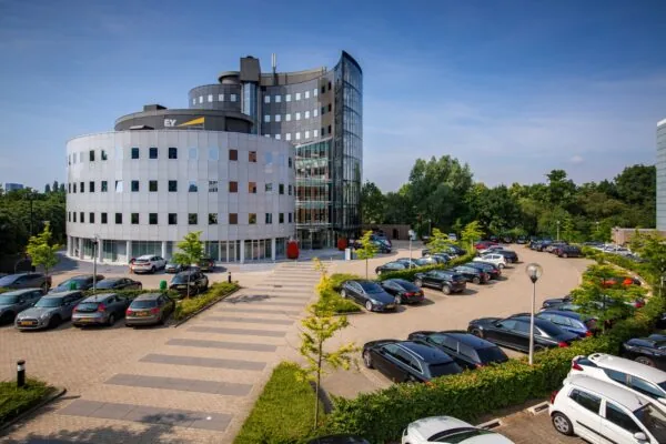 Kantoorgebouw van EY aan de Euclideslaan met aangrenzende parkeerplaats op een zonnige dag.
