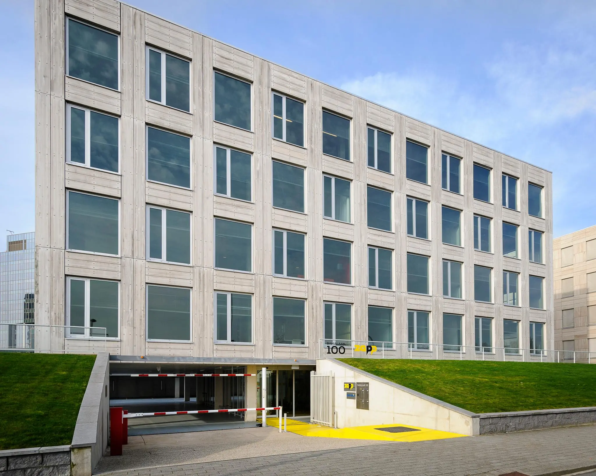Modern kantoorgebouw aan de Bahialaan met ondergrondse parkeergarage en grashelling.