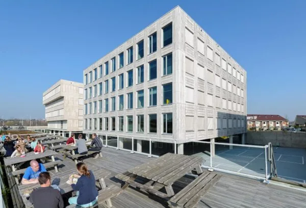 Moderne kantoorgebouwen aan de Bahialaan met mensen die lunchen op een zonnig dakterras met houten picknicktafels.