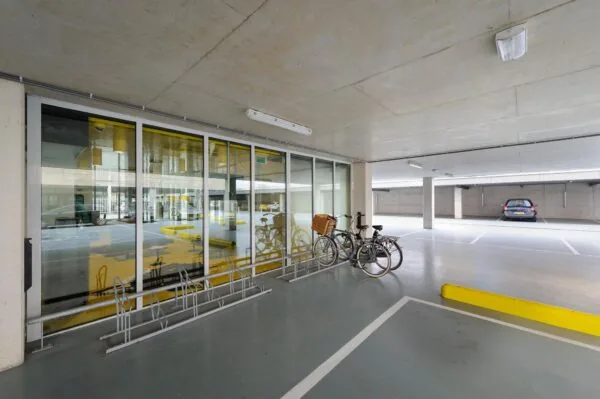 Overdekte parkeergarage aan de Bahialaan met fietsenrek, geparkeerde fietsen en auto.