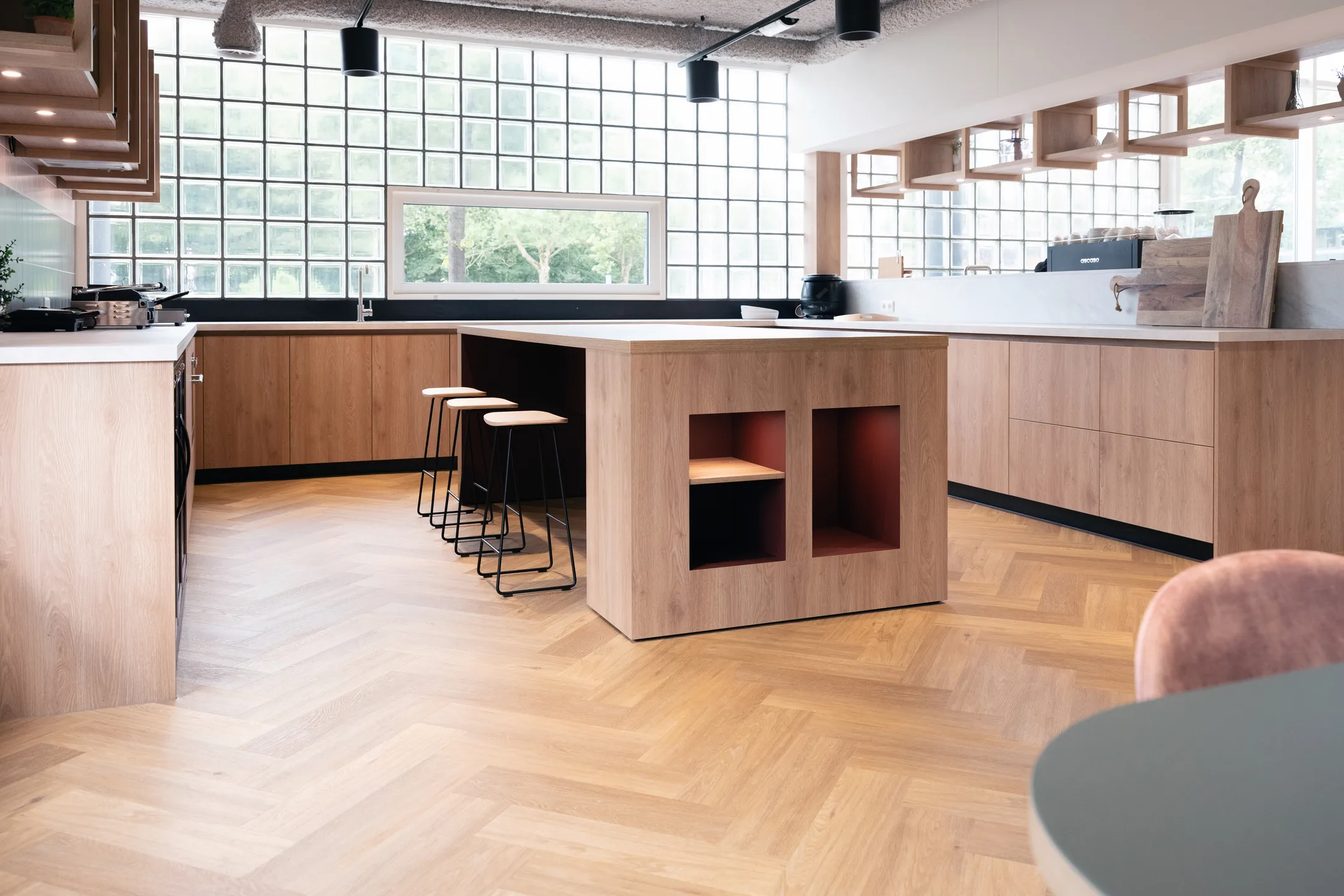 Een moderne keuken met houten kasten en een centraal kookeiland met barkrukken.